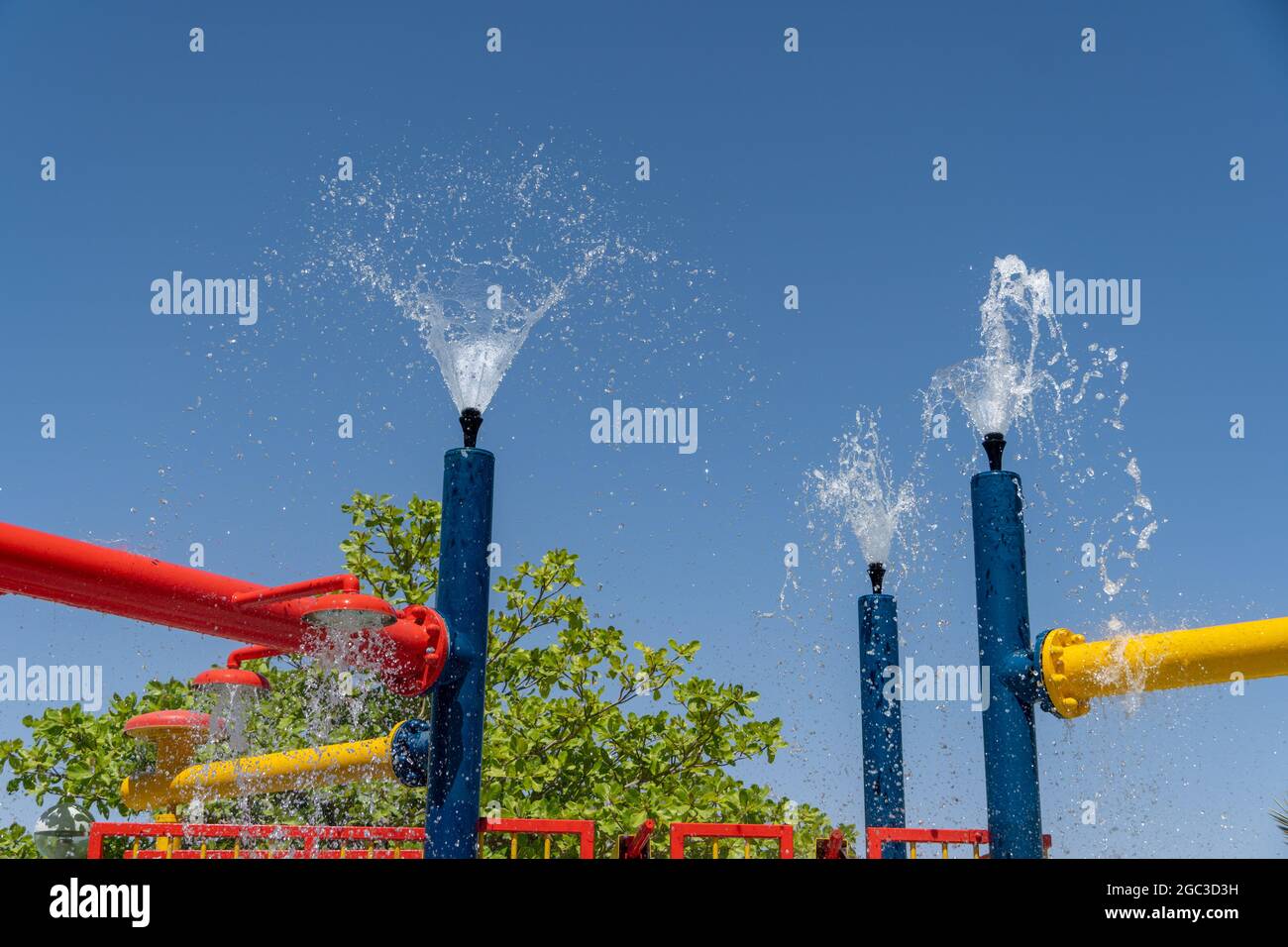 Tre sprinkler blu per il parco acquatico che spruzzano acqua sopra per il divertimento estivo dei bambini. Foto Stock