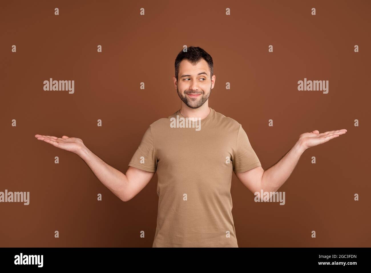 Foto ritratto brunetto uomo che indossa t-shirt pastello curioso confronto spazi vuoti isolato colore marrone sfondo Foto Stock