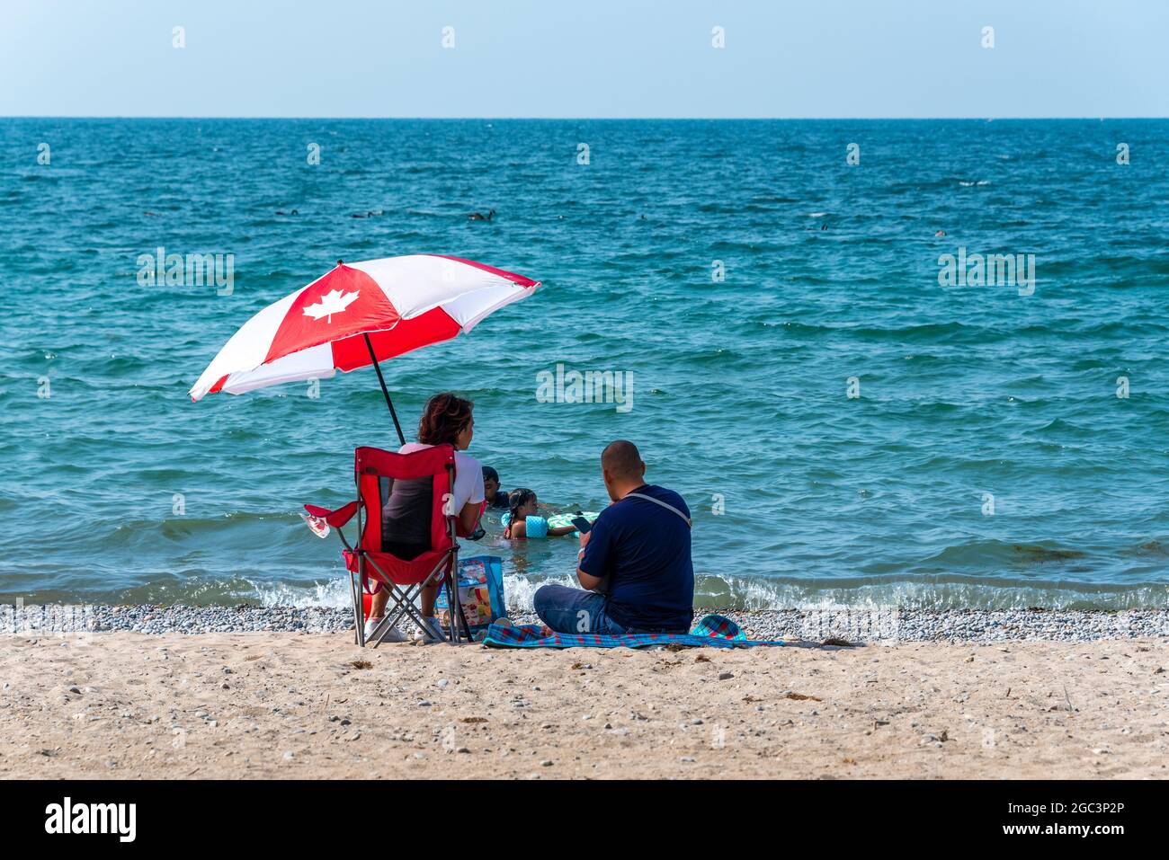 Persone canadesi con ombrello al Beachfront Park nella città di Pickering in Ontario, Canada. La spiaggia del lago Ontario è una famosa attrazione turistica Foto Stock
