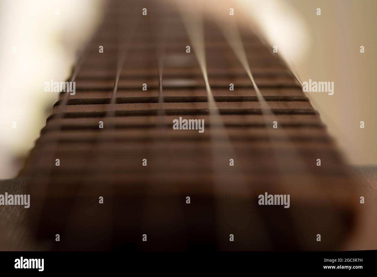 Dettaglio closeup di corde di chitarra in acciaio e tasti per fare musica. Fuoco selettivo su una soglia di chitarra. Foto Stock