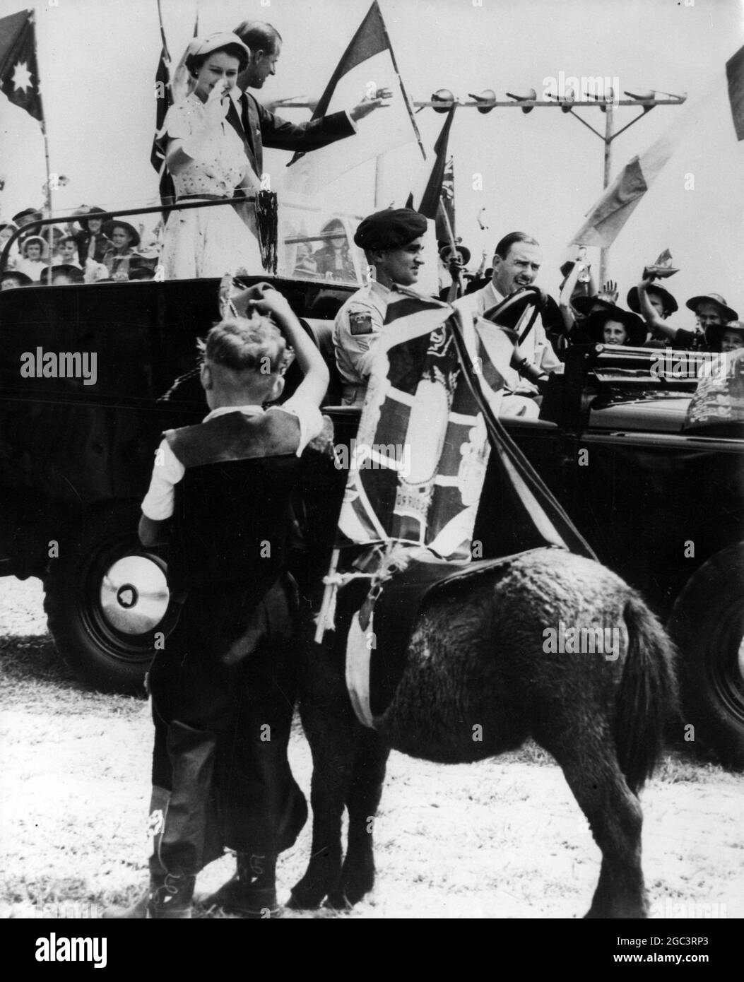 8 anni Billy Winzar , vestito da cowboy e con il suo pony Robin , ondeggia alla regina e duca di Edimburgo mentre passano nella loro Land Rover durante un Rally dei bambini a Mackay , Queensland , Australia . 20 marzo 1954 Foto Stock