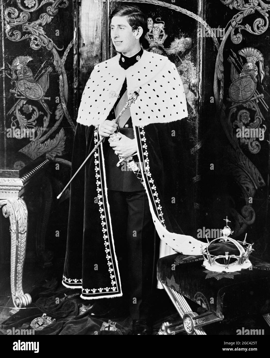 Il principe Carlo nella sua veste di investitura per quando diventa ufficialmente Principe di Galles, una cerimonia che sarà eseguita da sua Maestà la Regina Elisabetta II al Castello di Caernarvon, Galles, il 1 luglio 1969. In questa foto appositamente scattata da Norman Parkinson al Castello di Windsor, il Principe viene mostrato come apparirà prima dei suoi sudditi alla cerimonia. La sua Coronetta d'oro poggiata su un sedile di velluto accanto a lui, il Principe tiene da una parte la canna d'oro e dall'altra, la Spada di Ufficio, su un dito sulla sua mano sinistra indossa un anello d'oro. Tutti gli sono stati presentati dalla Regina come è stato investito. Ha donato la e Foto Stock