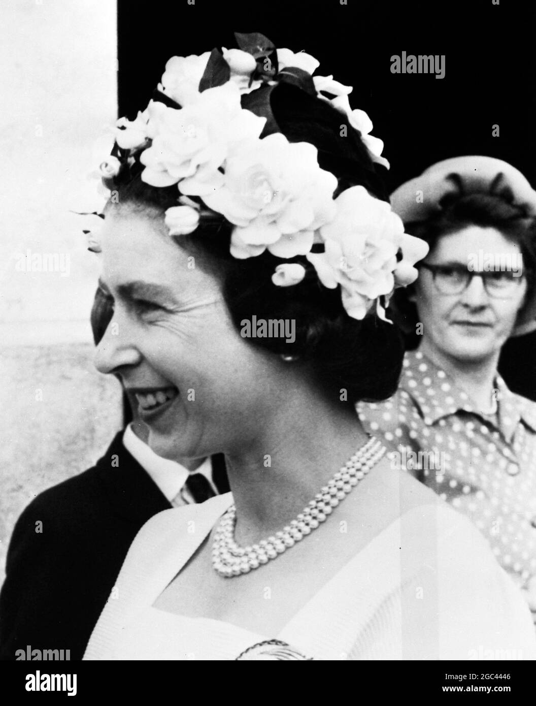 La regina Elisabetta II sorride gaily da sotto il suo cappello bianco Ring o' Roses mentre parla con gli agricoltori e le loro famiglie, mentre visita il Ducato di Cornovaglia fattorie vicino Saltash oggi. 25 luglio 1962 Foto Stock