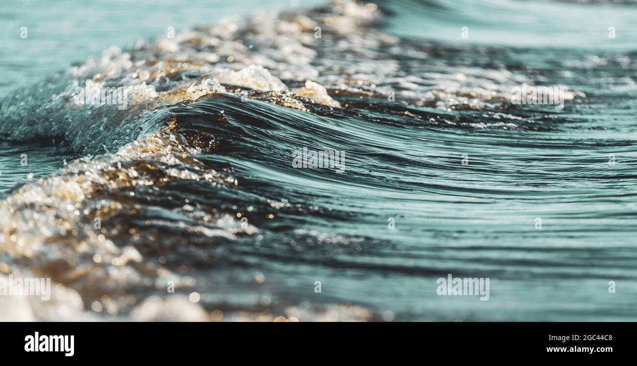 Un'onda che scorre dal mare scuro del Mar Baltico e dà belle linee nell'acqua scura. Foto Stock