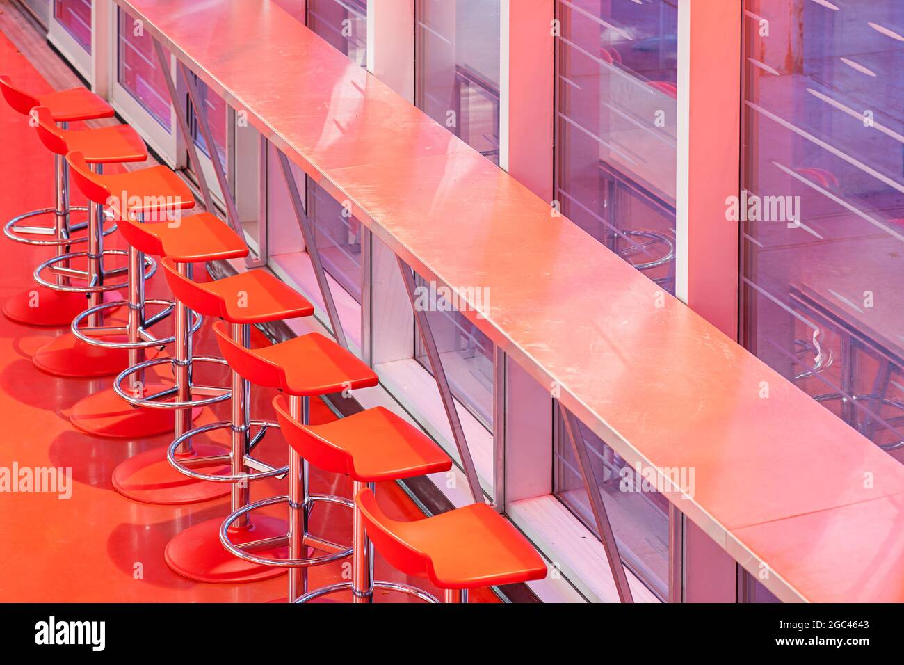 Interno di un ristorante con fila di sedie rosse Foto Stock