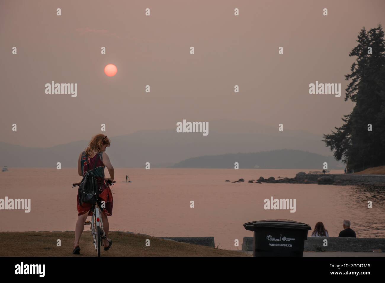 Vancouver, Canada - Agosto 1,2021: Smokey Sky su Vancouver da incendi. La foto mostra la donna che si trova su una seconda spiaggia di Stanley Park al tramonto Foto Stock