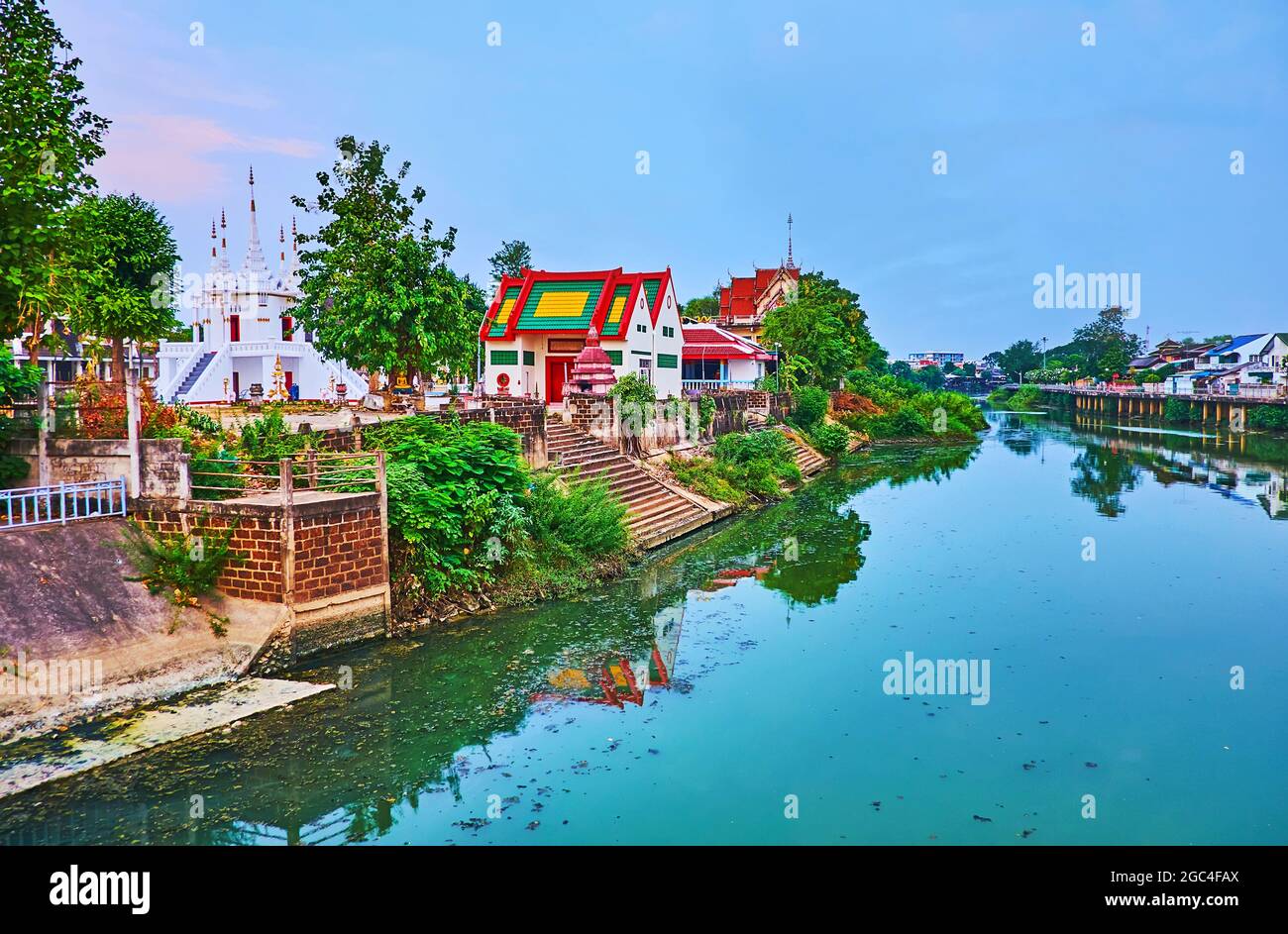 Il pittoresco tempio Wat Ko Walukaram con chedi intagliati bianchi, situato sulla riva verde del fiume Wang a Lampang, Thailandia Foto Stock