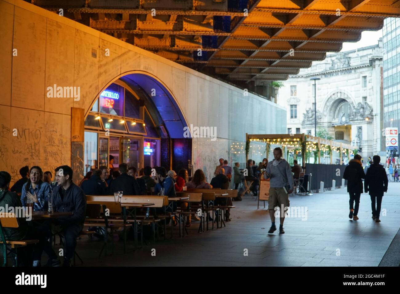 Londra, Regno Unito, 6 agosto 2021: Venerdì sera sulla South Bank di Londra consente ai bevitori di avere tempo per una pinta e per socializzare al Waterloo Tap, con la stazione di Waterloo in background pronta a consentire ai bevitori di tornare a casa in modo sicuro con i mezzi pubblici. Anche se il footfall non è così alto come nei periodi pre-pandemic, ci è ancora una buona vibrazione di notte di venerdì come la gente attende con impazienza al fine settimana. Anna Watson/Alamy Live News Foto Stock