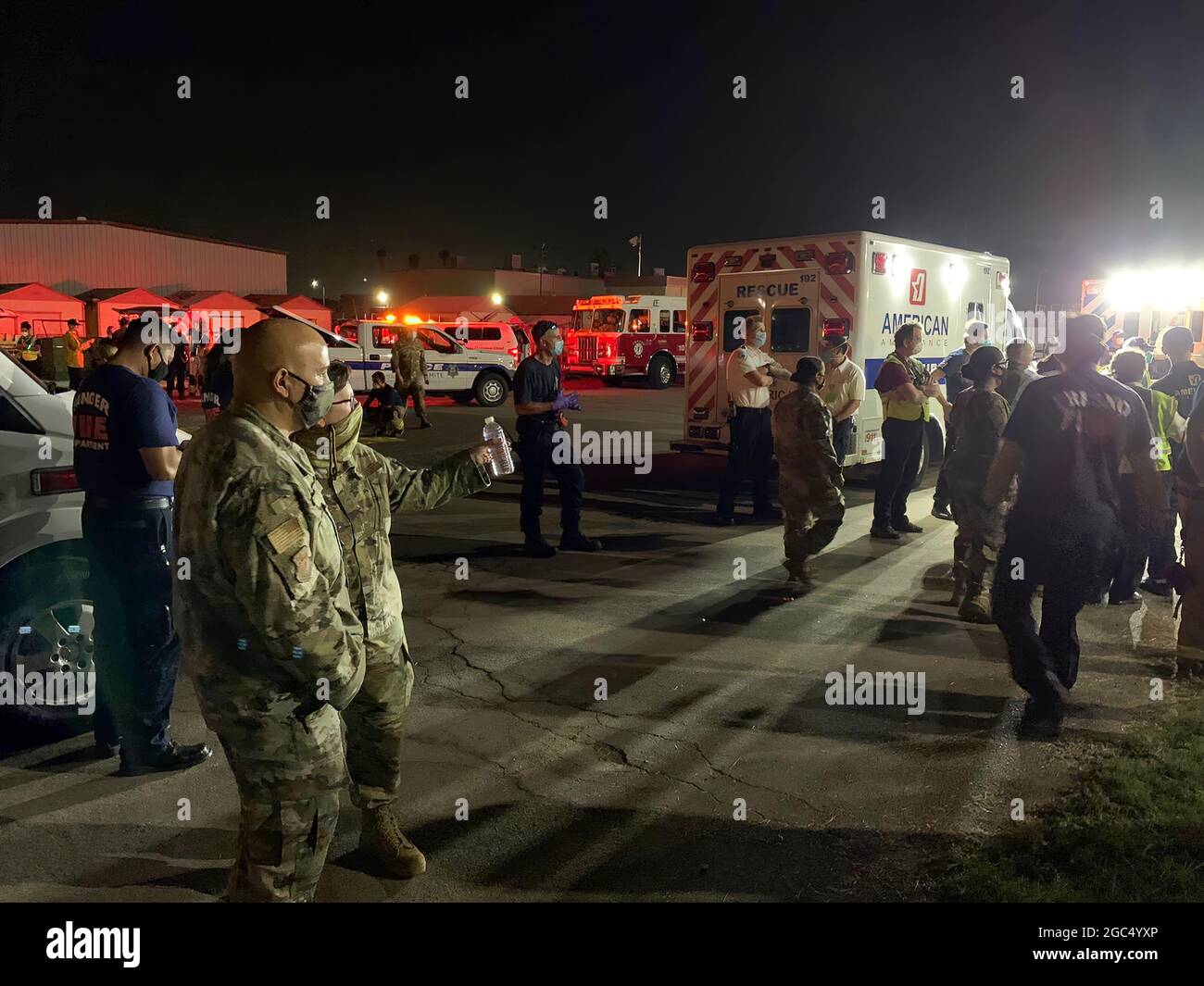 I guardiani nazionali della California, il dipartimento dei vigili del fuoco di Fresno e i servizi medici di emergenza della contea di Fresno attendono l'arrivo di un elicottero CH-47 Chinook della Brigata dell'aviazione di combattimento che trasporta gli evacuati dal fuoco del torrente alla linea di volo del 1106 del gruppo di manutenzione dell'aviazione del supporto del teatro a Fresno, California, 6 settembre 2020. Il Dipartimento militare della California ha evacuato oltre 200 persone lungo il bacino idrico di Mammoth Pool quando l'incendio del Creek è esploso in dimensioni. (STATI UNITI Air National Guard foto di Capt. Jason Sanchez) Foto Stock