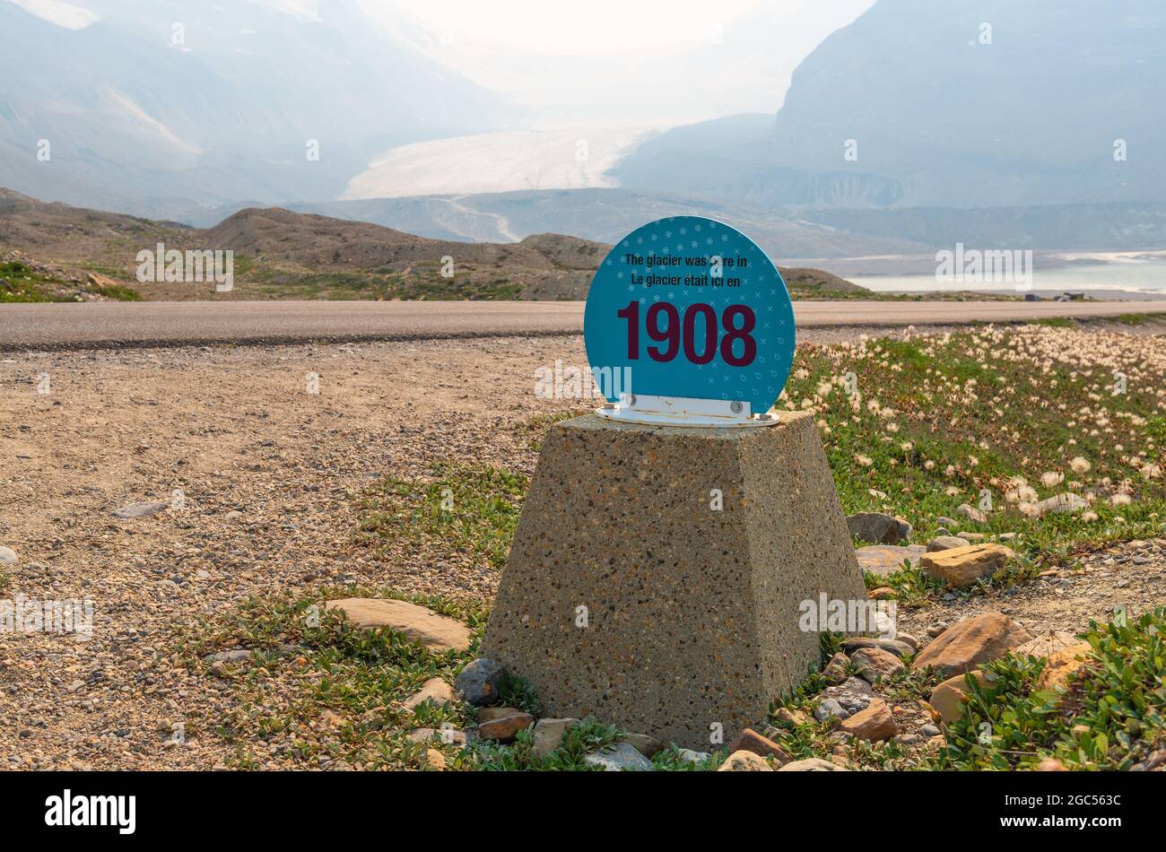 Ghiacciaio di Athabasca con il cartello del miglio che mostra l'effetto del cambiamento climatico sul ritiro del ghiaccio dal 1908, con incendi di fumo soffia nell'aria, Alberta, Canada. Foto Stock