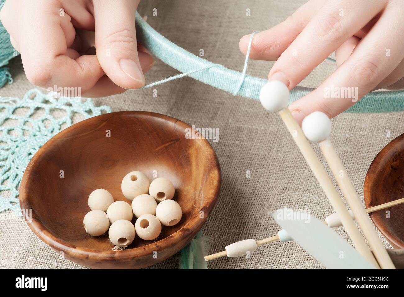 Closeup di mani femminili che hanno il catcher sogno assemblato. Composizione artigianale di piume, perline, utensili per fai da te Foto Stock