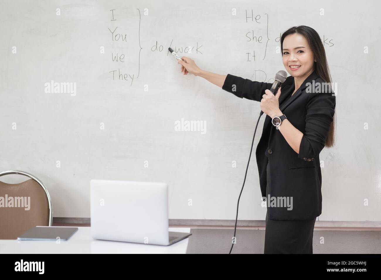 Foto ritratto di un'amica e sicura insegnante asiatica in una divisa nera da lavoro con un tablet digitale e un computer portatile per insegnare la lan moderna Foto Stock