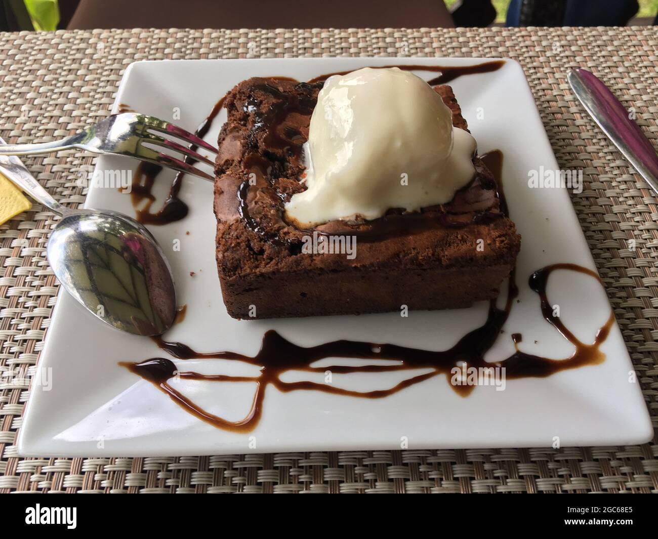 Una serva di torta brownie al cioccolato con gelato al cocco su piatto da portata bianco. Foto Stock