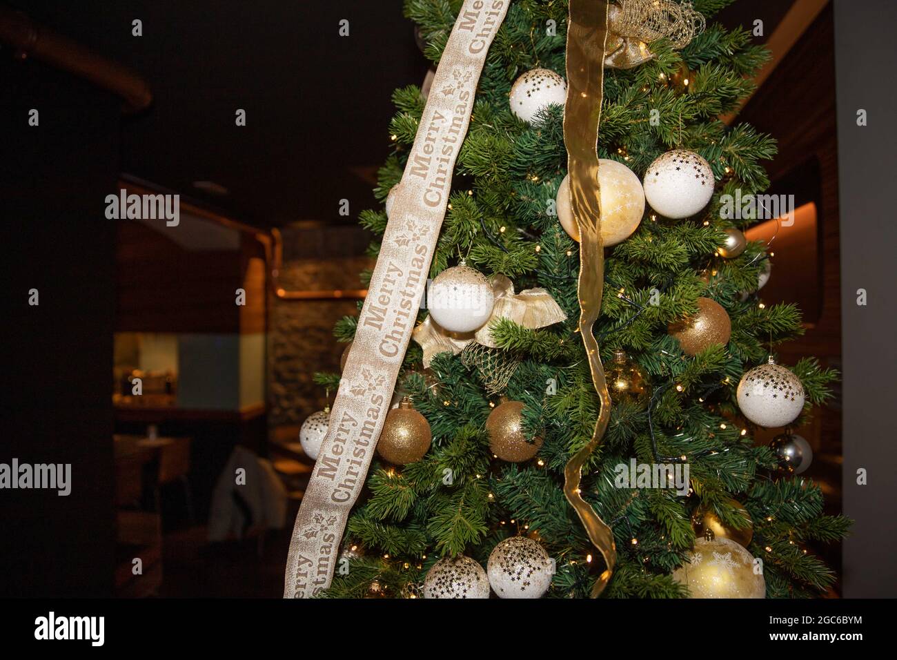 Primo piano di un albero di Natale decorato con luci e palline di Natale, e un nastro che dice 'buon Natale'. Albero di Natale interno. Foto Stock