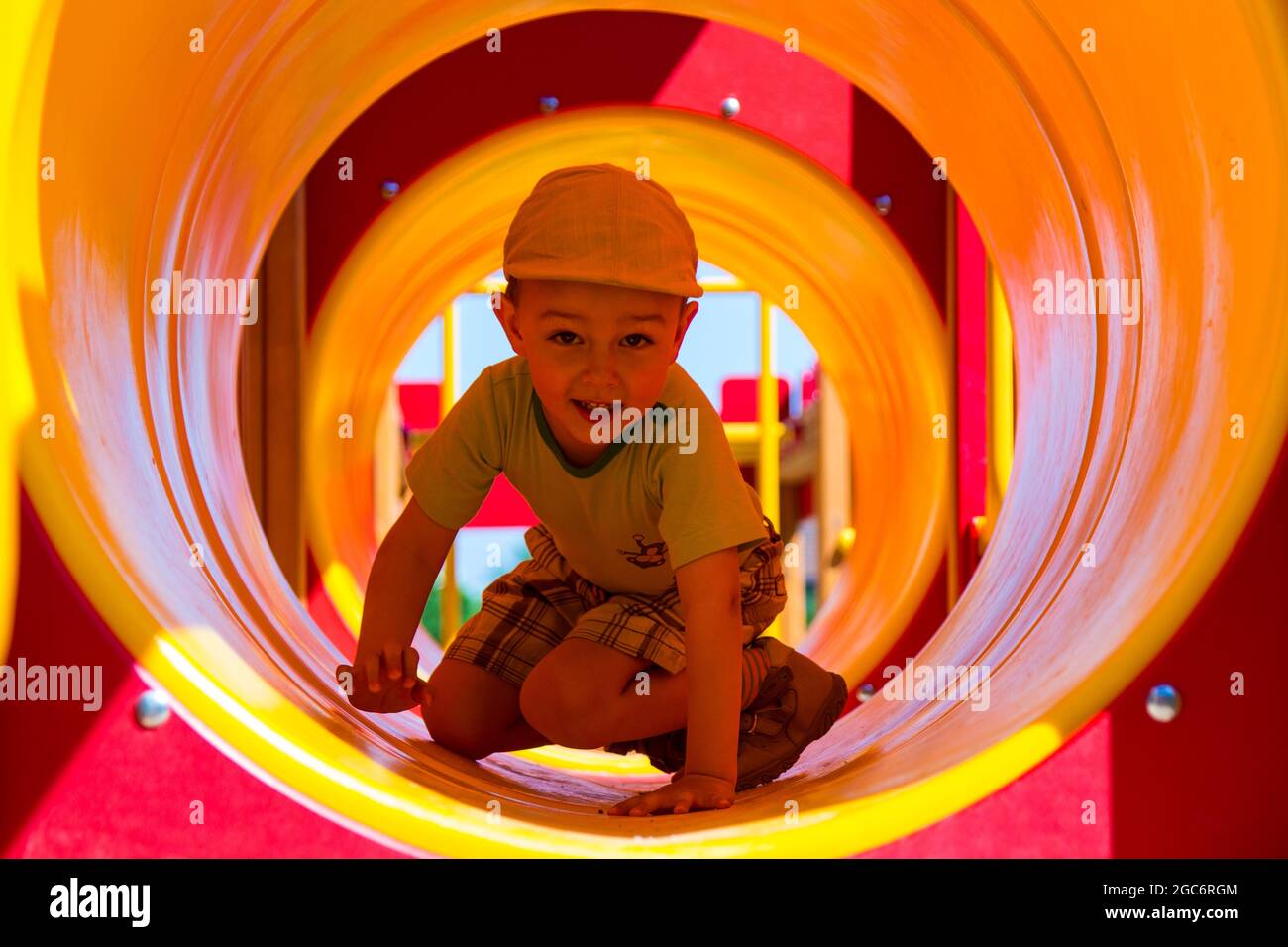 bambino di 4 anni che strisciava nel tubetto del giocattolo nel parco giochi verso la macchina fotografica Foto Stock
