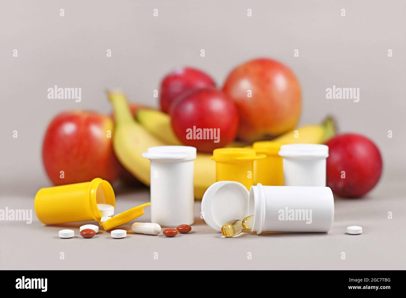 Integratori alimentari capsule e pillole con con bottiglie di plastica di fronte alla frutta Foto Stock