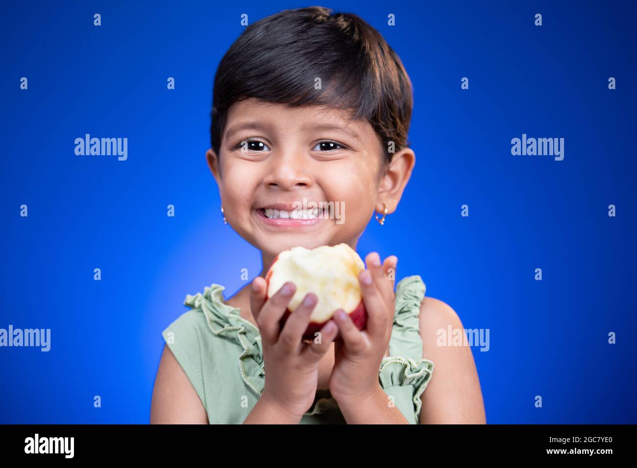 Ritratto del capretto della ragazza che tiene la mela su sfondo blu - concetto di consumo sano e di stile di vita Foto Stock