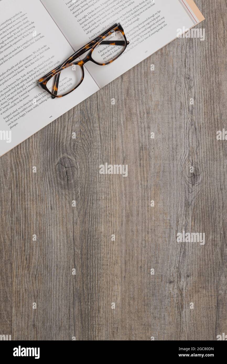 un paio di occhiali da lettura seduti sopra un libro aperto su un tavolo di  legno, visto dall'alto Foto stock - Alamy