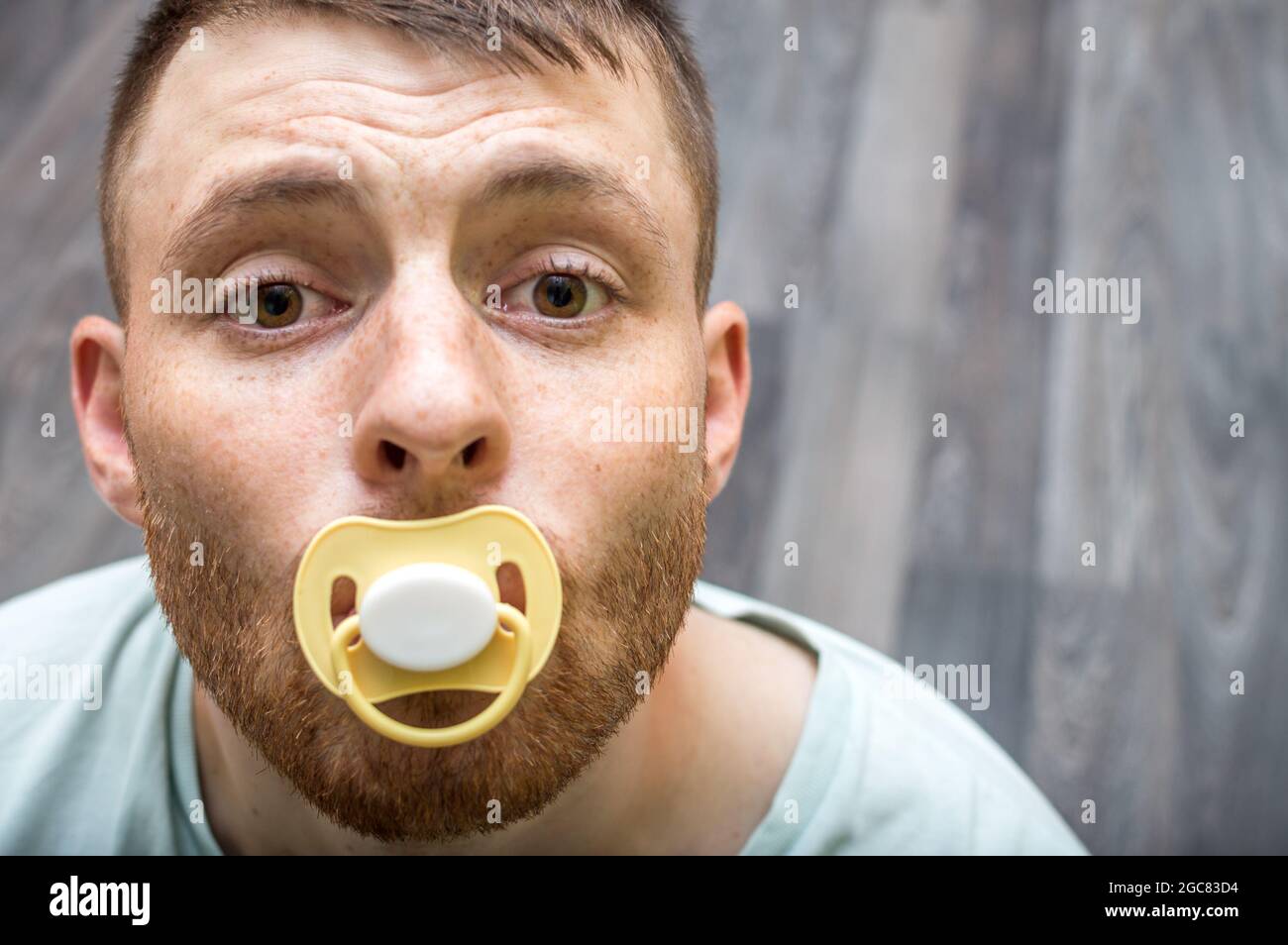 Ritratto di un giovane con un manichino in bocca. Concetto di infantiismo Foto Stock