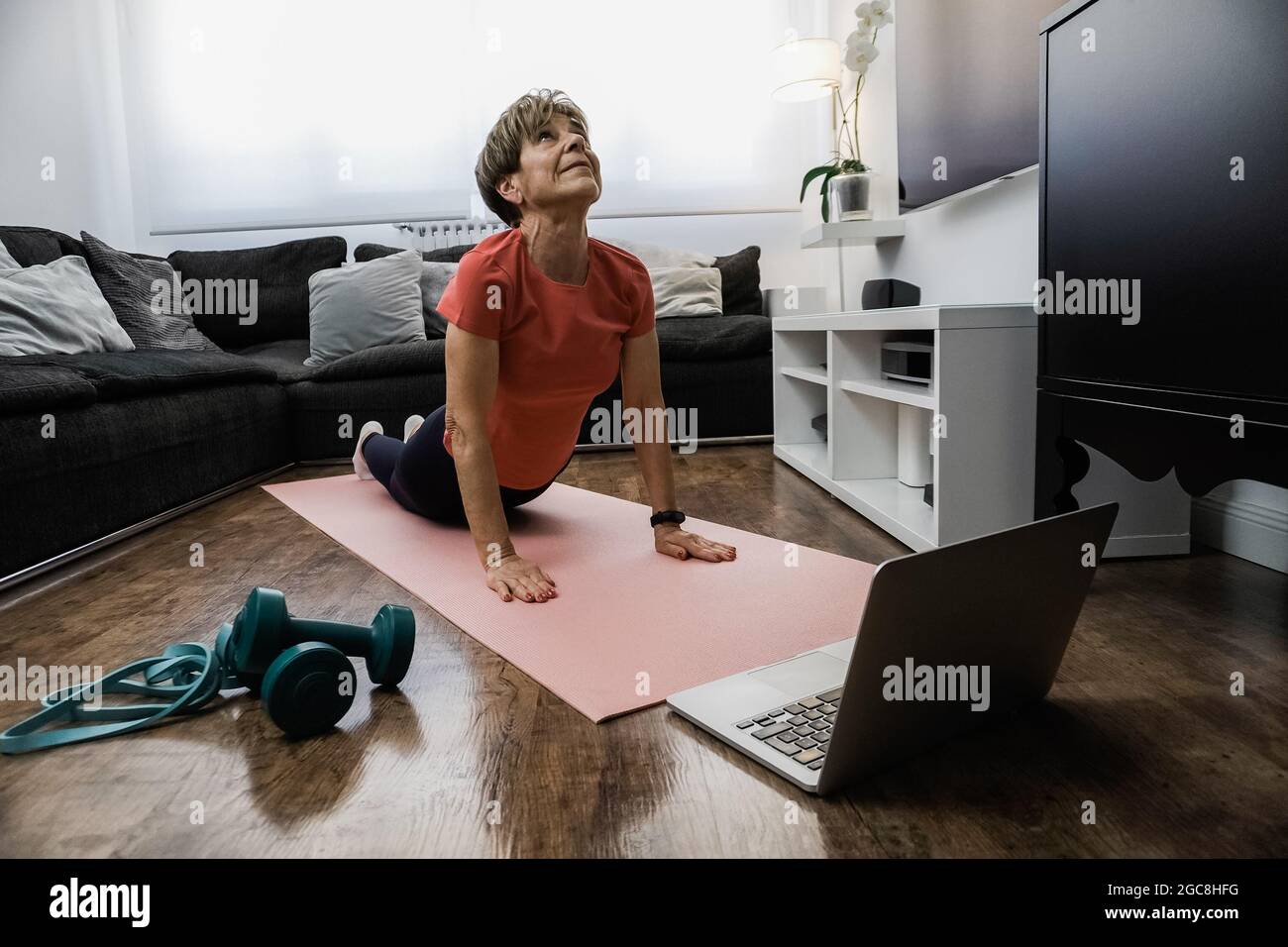 Senior woman doing online yoga workout class a casa - concetto di stile di vita per anziani sani e sportivi - Focus on face Foto Stock