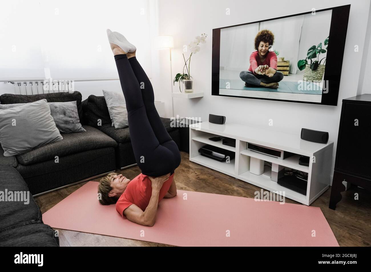 Senior woman doing online yoga sport workout class a casa - sano e benessere concetto di stile di vita anziani - Focus on face Foto Stock
