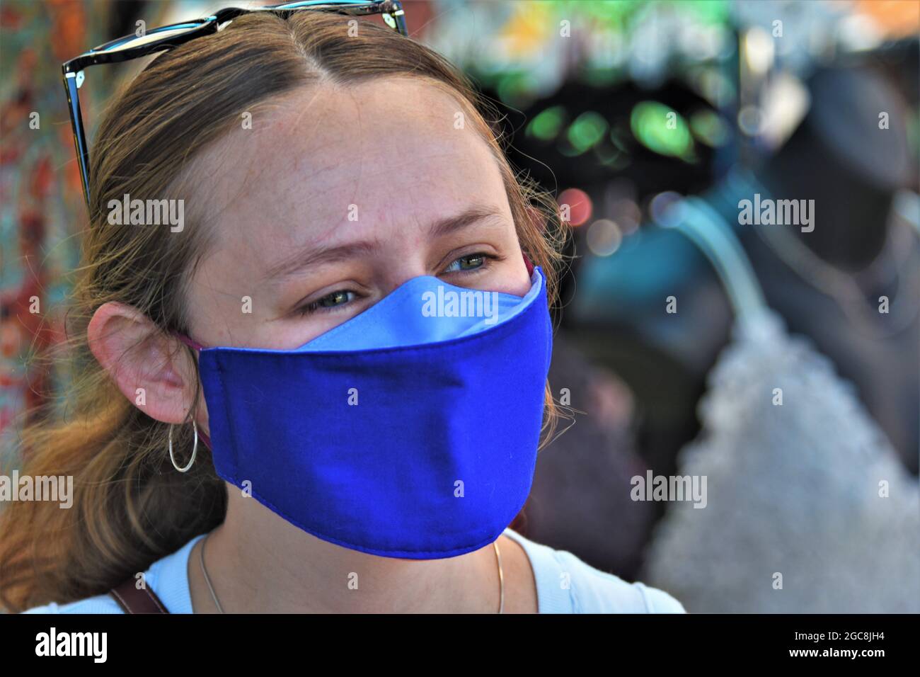 Giovane donna che indossa una maschera in una vendita pubblica di strada nel nord della California durante la recente ripresa di infezioni Corona-19 Foto Stock