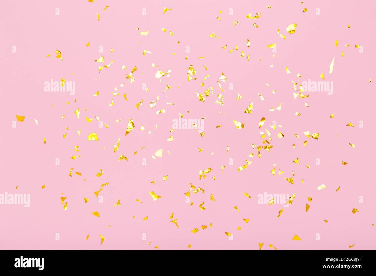 I confetti con glitter dorati brillano su sfondo rosa pastello. Disposizione piatta, vista dall'alto. Festa, festa, sfondo festa. Foto Stock