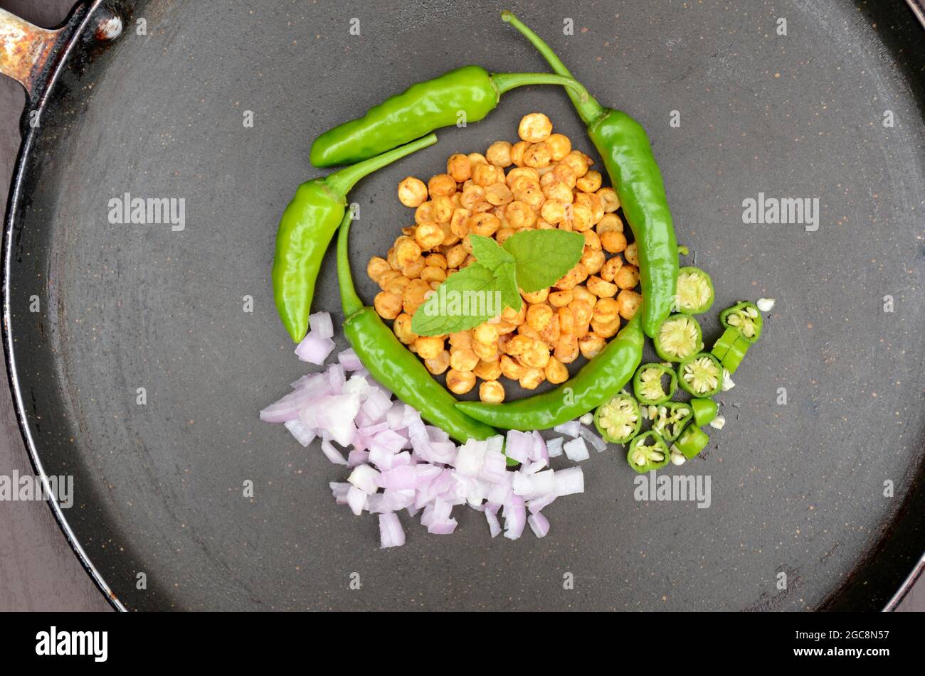 closeup le lenticchie giallo bengala fritte con menta, verde peperoncino, cipolla a fette, su sfondo nero fuori fuoco. Foto Stock