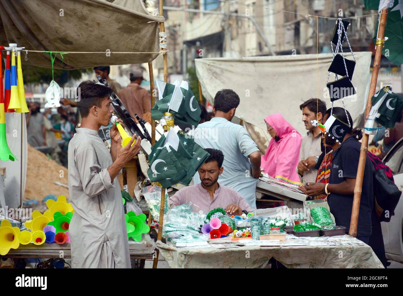 Bandiere del Pakistan, i raggruppamenti, le camicie stampate ed altri  articoli stanno vendendo sul lato della strada stalla in connessione del  giorno di indipendenza del Pakistan che viene avanti, a Karachi il
