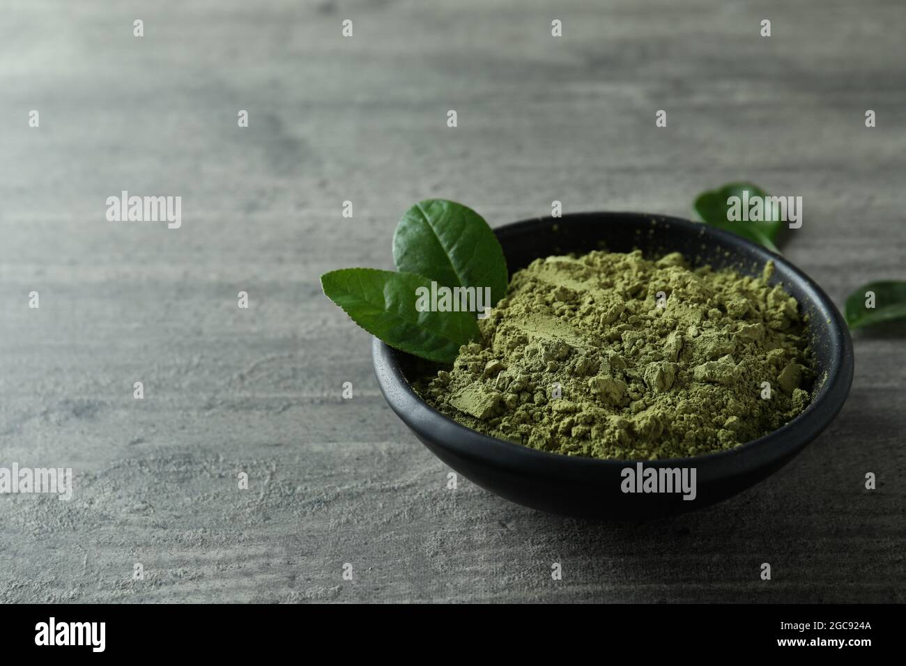 Piatto di polvere matcha su fondo grigio testurizzato Foto Stock