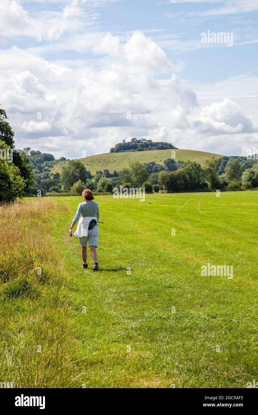 Donna che cammina lungo il fiume Thame lungo percorso che si avvicina Wittenham Clumps nel rurale Oxfordshire Foto Stock