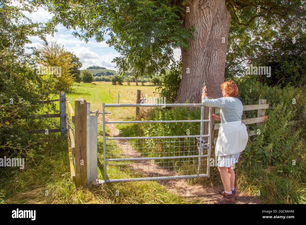 Donna che cammina lungo il fiume Thame lungo percorso che si avvicina Wittenham Clumps nel rurale Oxfordshire Foto Stock