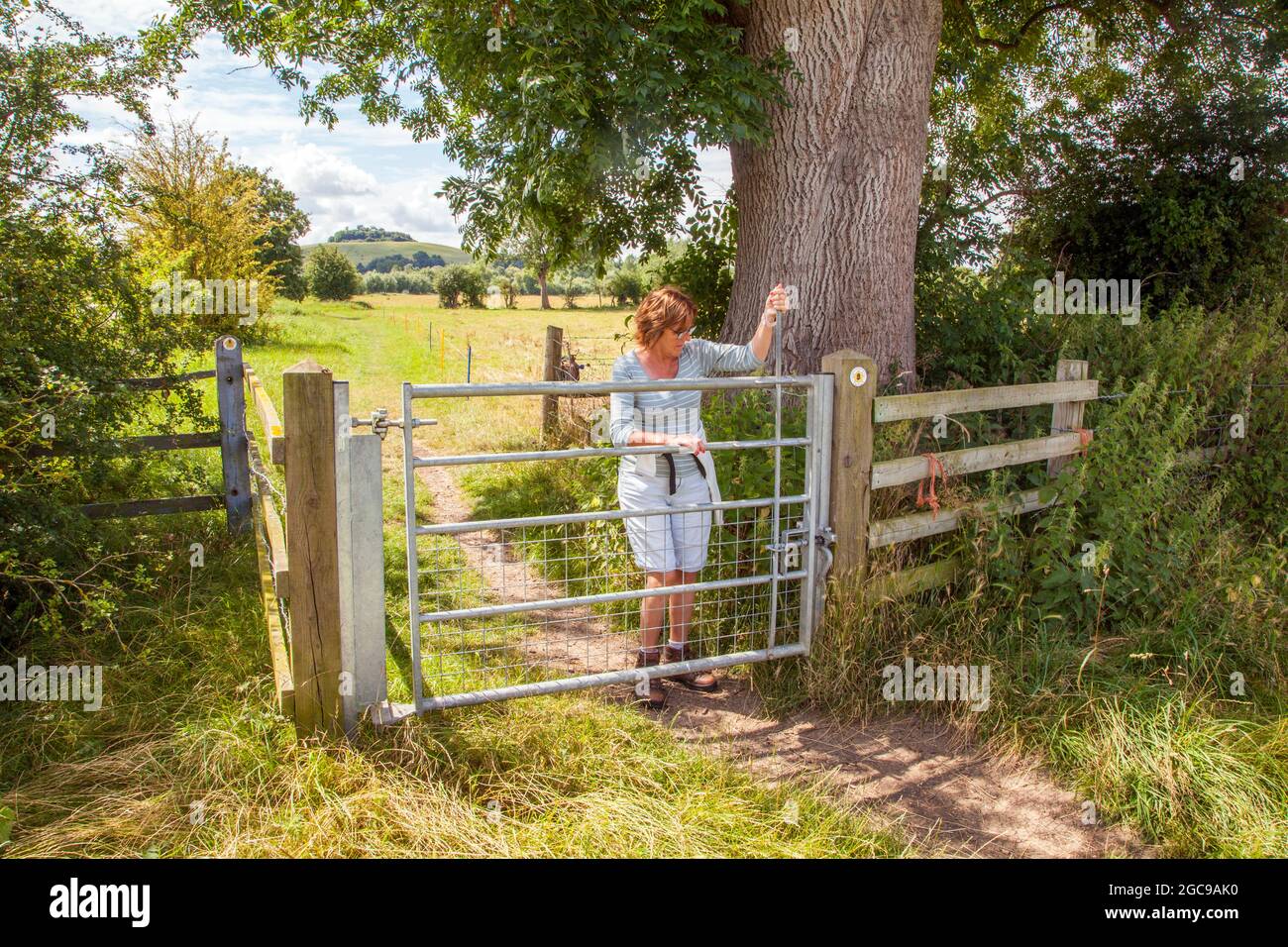 Donna che cammina lungo il fiume Thame lungo percorso che si avvicina Wittenham Clumps nel rurale Oxfordshire Foto Stock