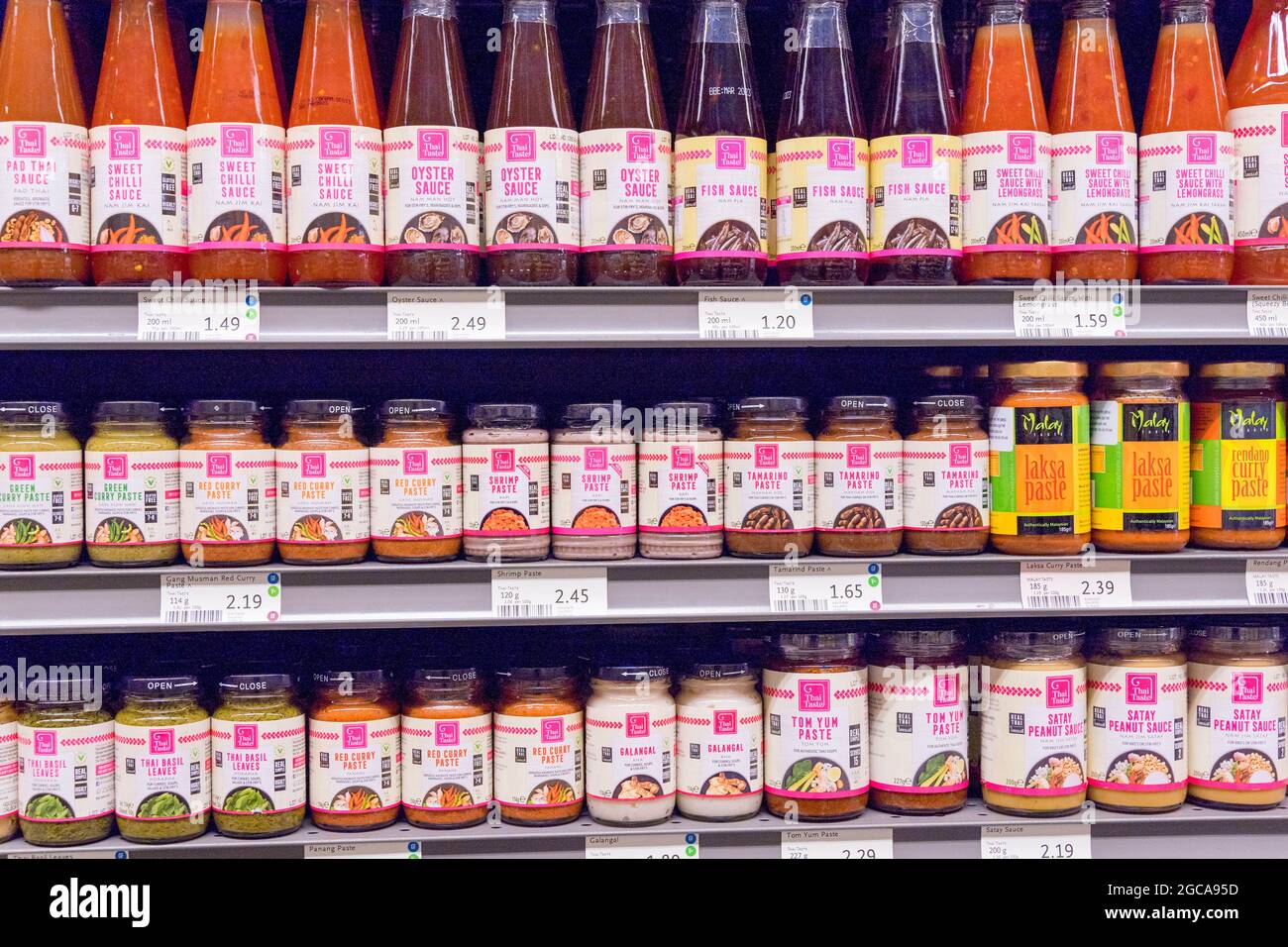 Molte bottiglie di pasta tailandese, salsa di pesce visualizzato sullo scaffale per la vendita al supermercato alimentare intero Londra Inghilterra Foto Stock