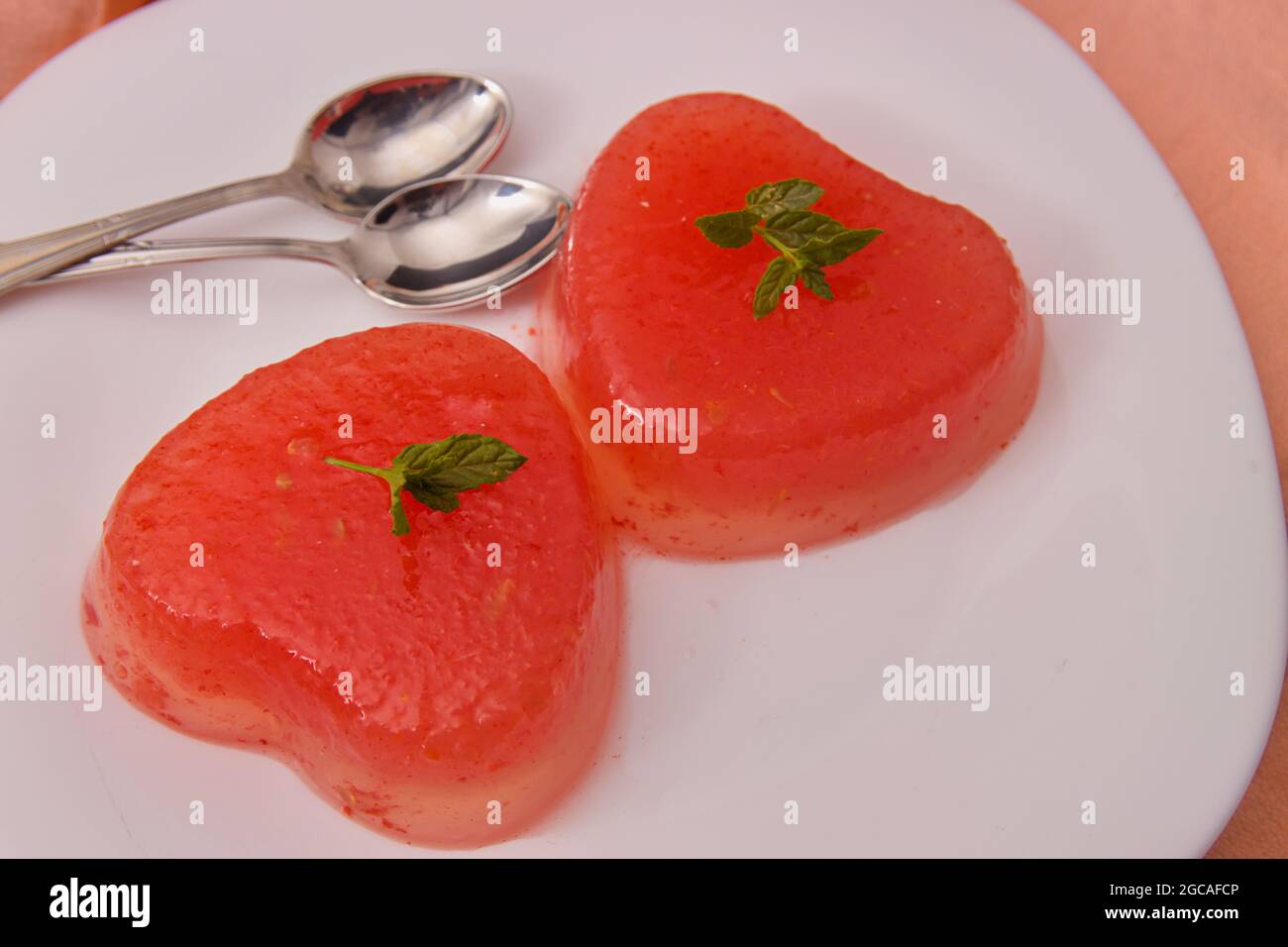 Primo piano di alcune gelatine a forma di cuore su un piatto per condividere il dolce con una coppia Foto Stock