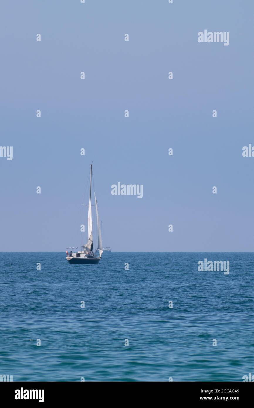 Marinai sull'oceano, barca a vela che naviga all'orizzonte Foto Stock