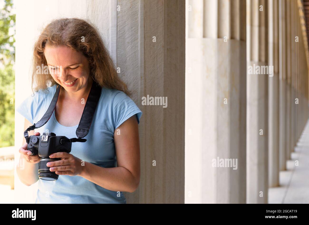 Turismo a Stoa di Attalos, Atene, Grecia, Europa. Felice giovane donna riproduce le immagini in macchina fotografica alle colonne greche antiche. Questo luogo è un punto di riferimento di Athen Foto Stock