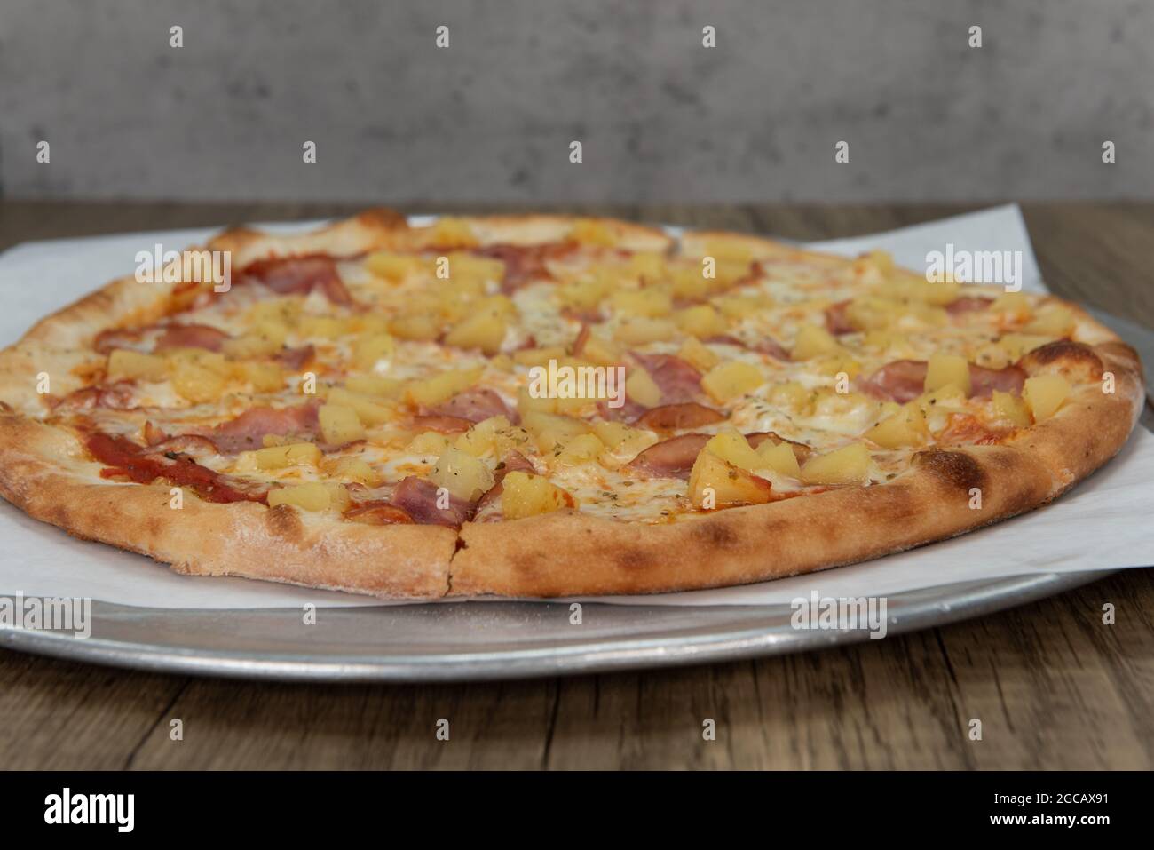 Pizza hawaiana all'ananas con farciture di verdure e crosta croccante per un pasto completo in famiglia. Foto Stock
