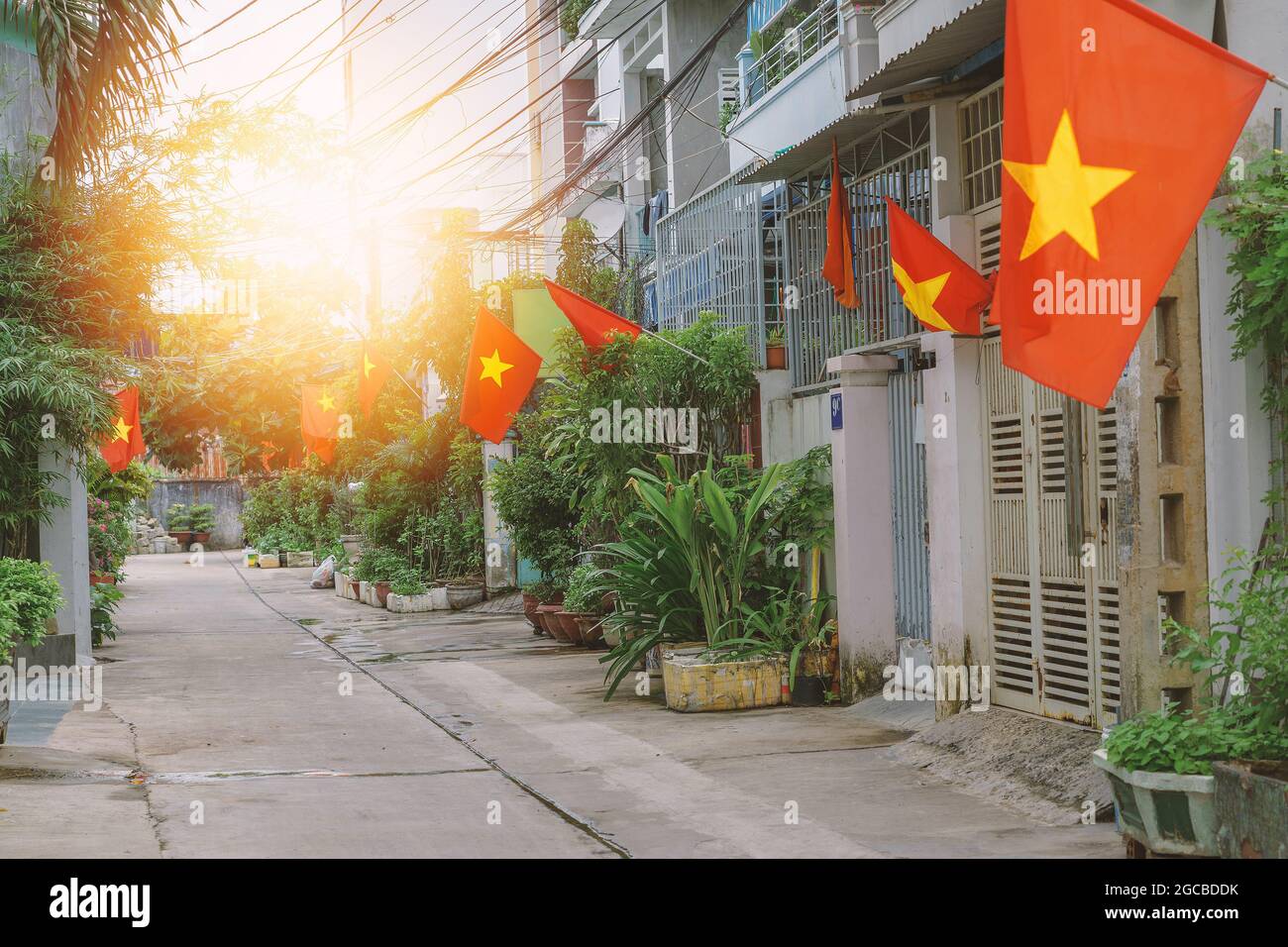 Bandiere lungo una piccola strada in Hanoi. Bandiere nazionali vietnamite in case strette corsie residenziali. Patriottismo dei cittadini durante la celebrazione di Foto Stock