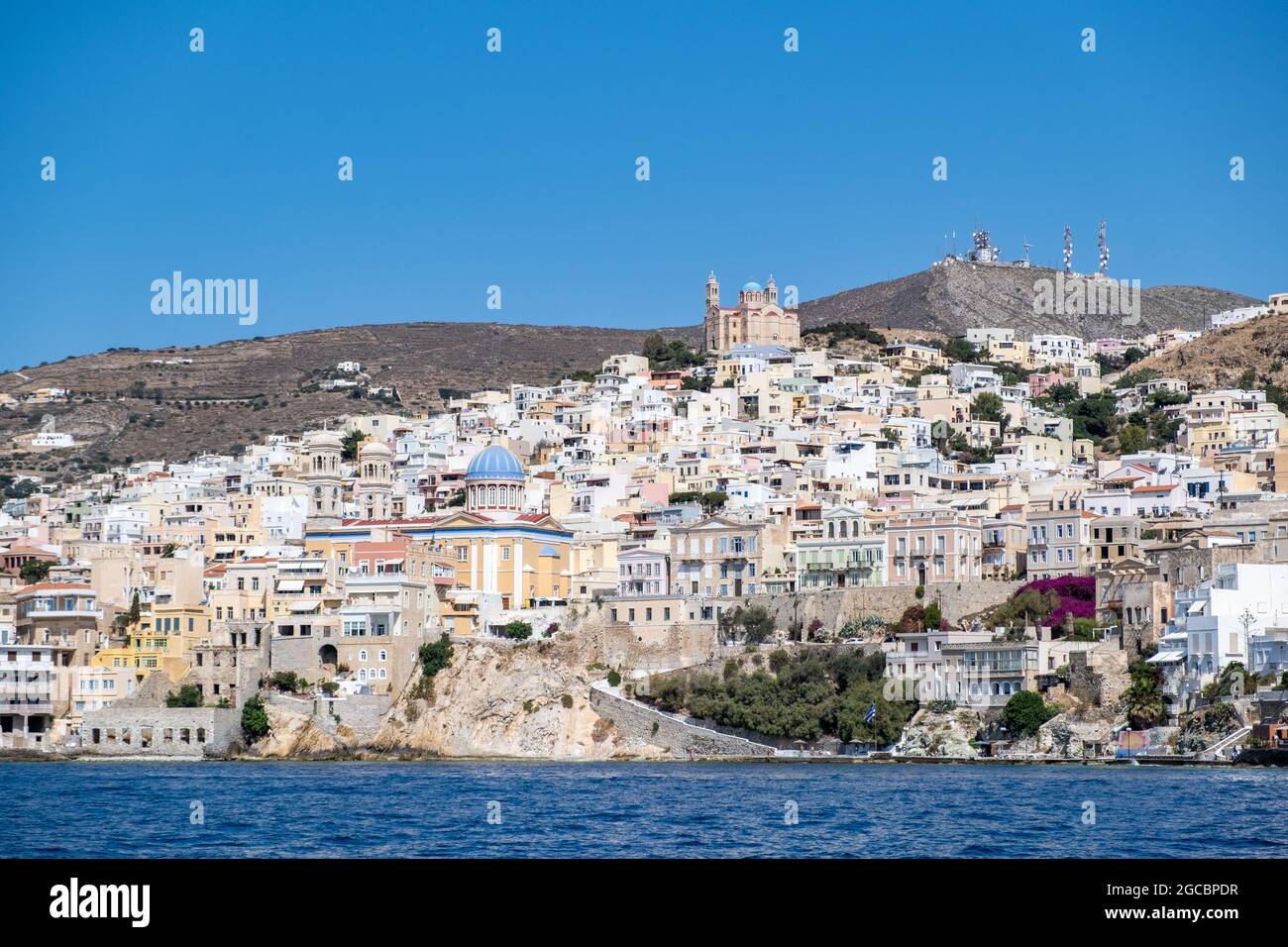 Isola di Syros, Cicladi, Grecia. Vista panoramica su Siros o sullo sfondo della città di Syra. Edifici tradizionali in collina sul mare. Greco sole mar Egeo, estate Foto Stock