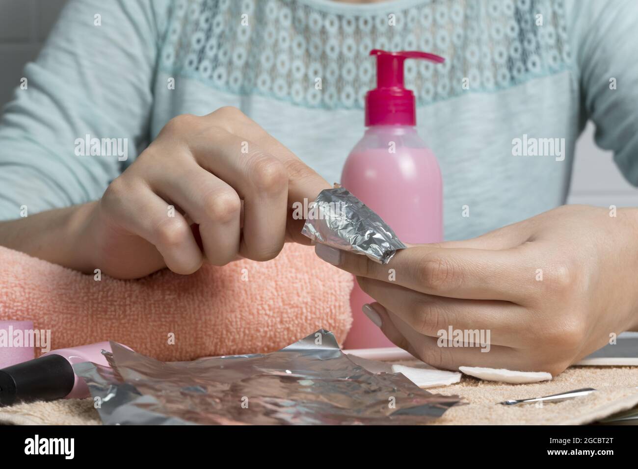 Rimuovere il gel lucidante con un foglio di alluminio. La donna versa rimuovere il liquido su un batuffolo di cotone, lo mette su un'unghia e avvolge la lamina. Rimozione dei chiodi di gommalacca. Fai un manicur Foto Stock