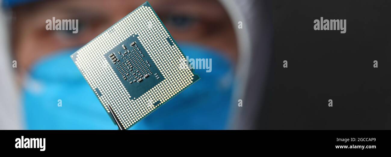 Lo scienziato mascherato tiene un microcircuito in forcipe Foto Stock