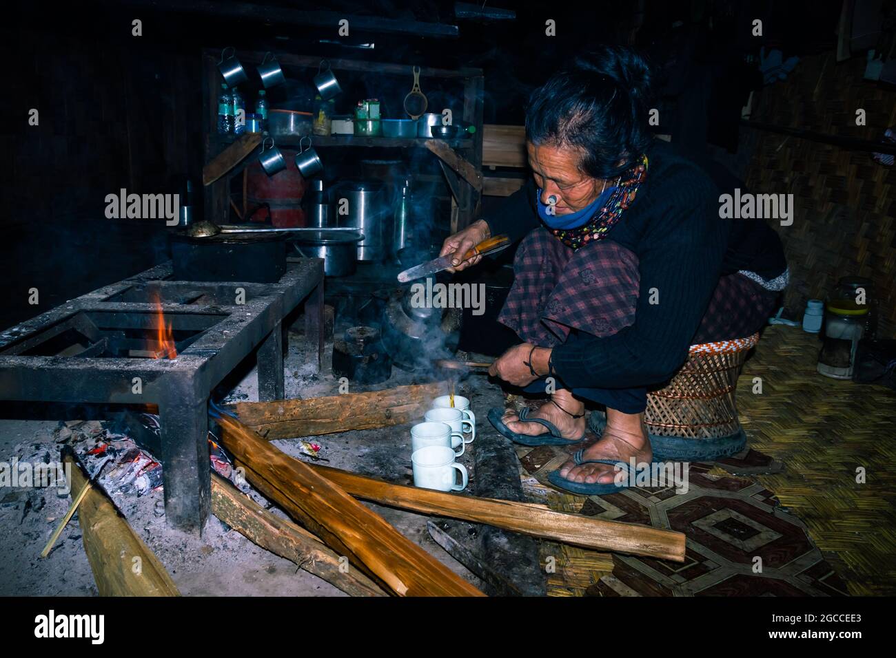 la signora tribale di apatani che fa il tè alla sua casa vicino al fuoco luogo alla sera immagine è presa a ziro arunachal pradesh india. è una della tribù più antica di Foto Stock