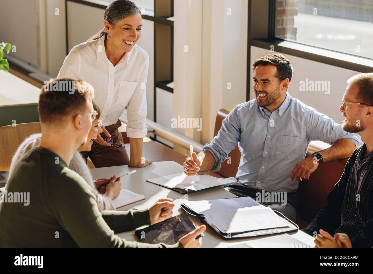 Manager che discute il progetto e condivide le idee con i colleghi. Sorridente dirigente donna che parla in riunione. Foto Stock