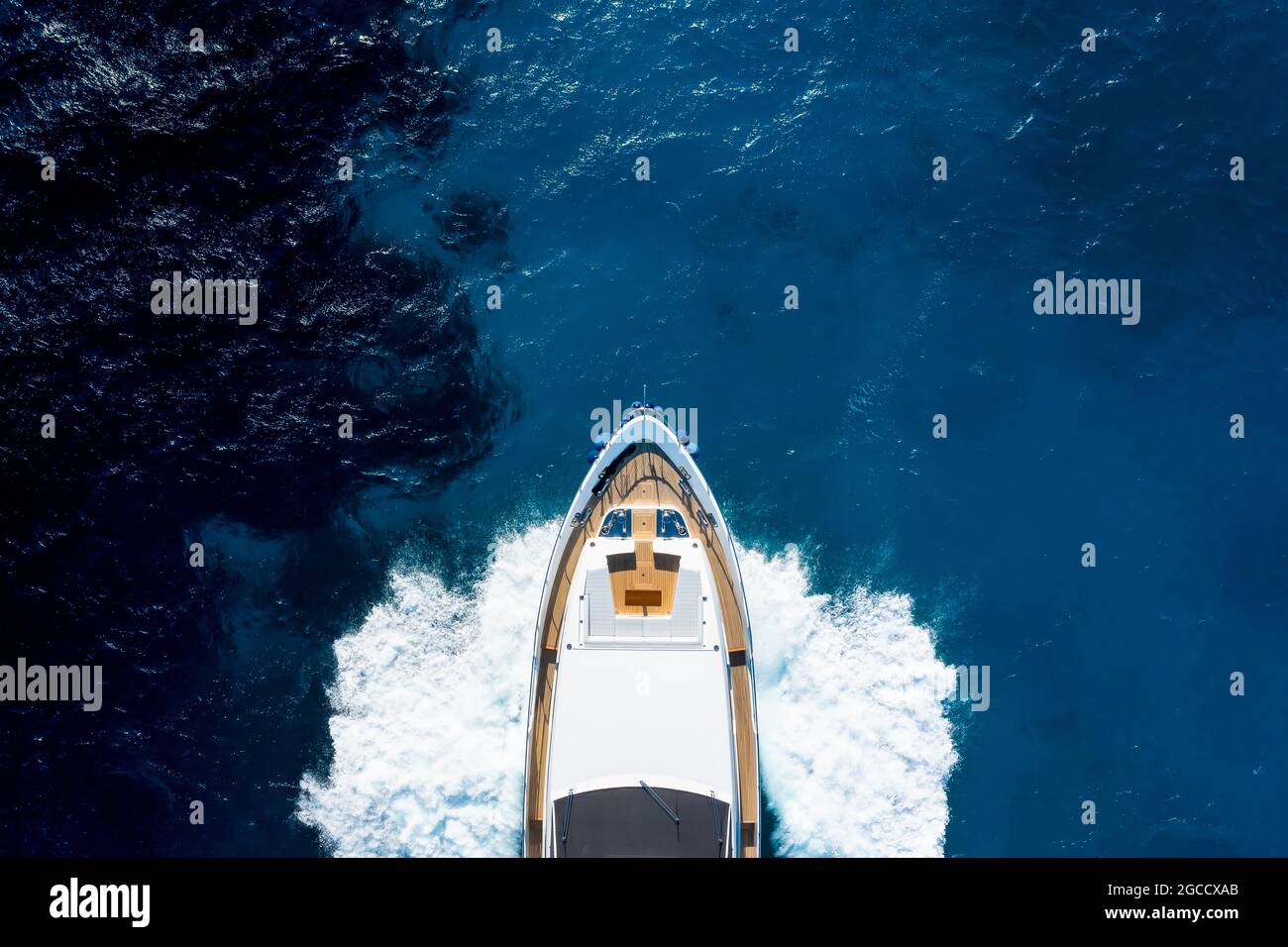 Vista dall'alto, splendida vista aerea di uno yacht di lusso che naviga su un'acqua blu con onde che si infrangono sulla prua della barca. Costa Smeralda, Sardegna. Foto Stock