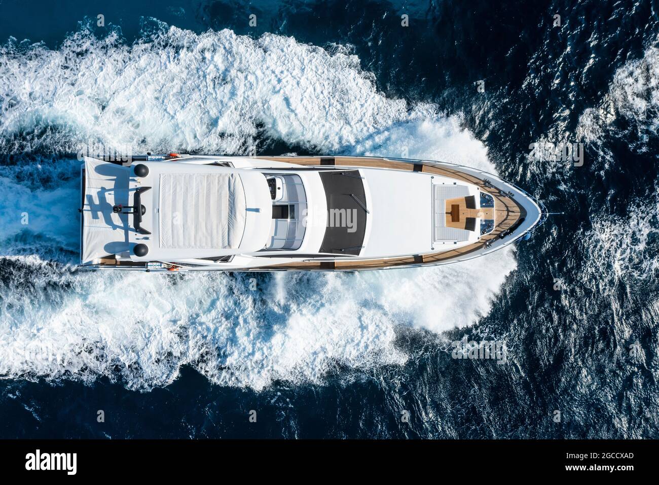 Vista dall'alto, splendida vista aerea di uno yacht di lusso che naviga su un'acqua blu con onde che si infrangono sulla prua della barca. Costa Smeralda, Sardegna. Foto Stock