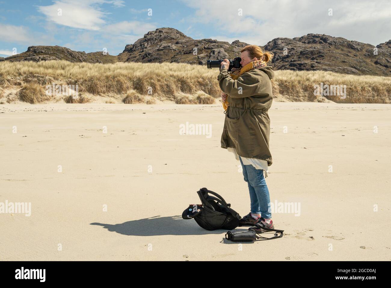 Fotografa donna con teleobiettivo sulla remota spiaggia dell'isola scozzese Foto Stock