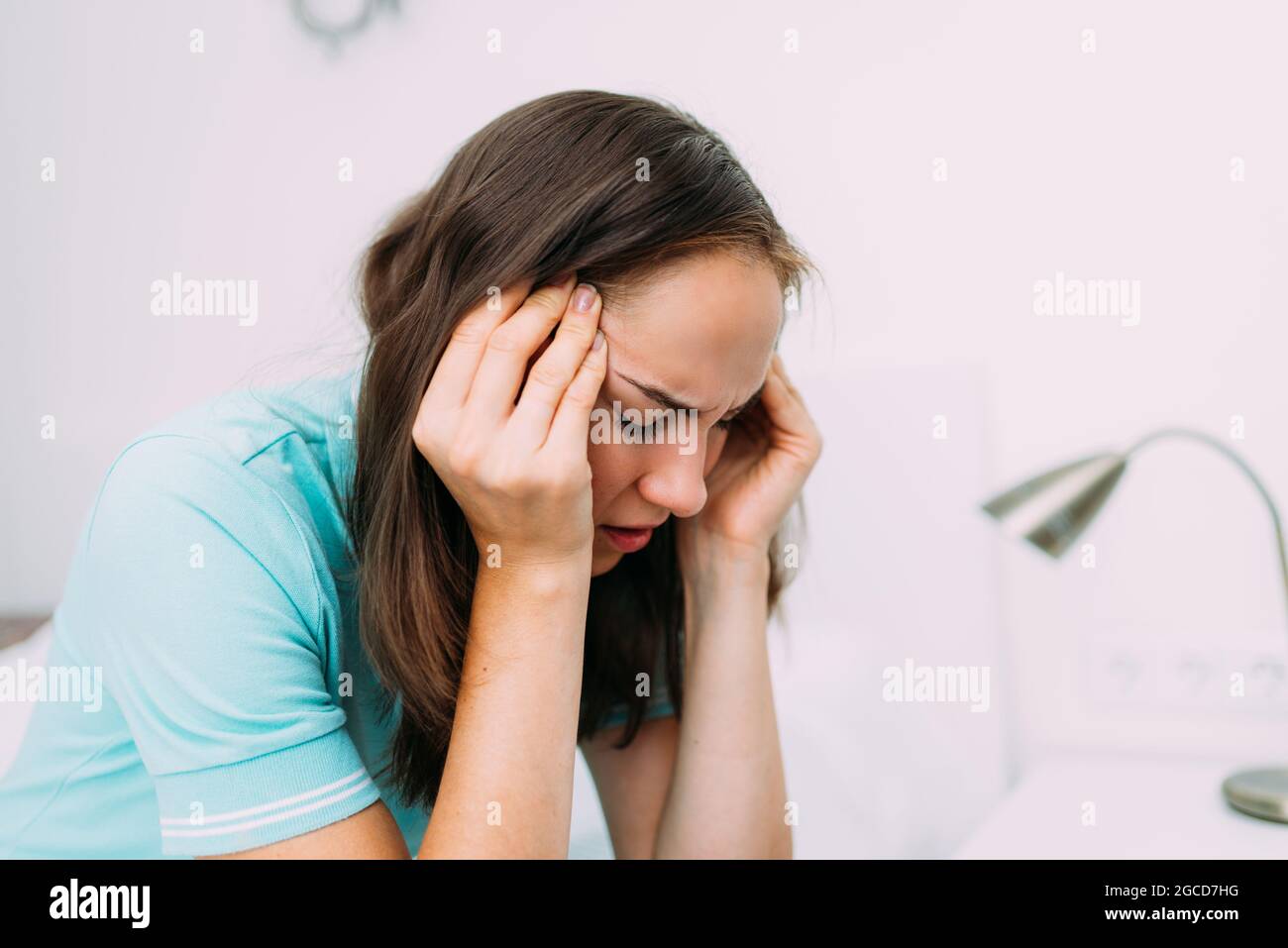 Donna caucasica seduta a casa e affetta da mal di testa. Foto Stock
