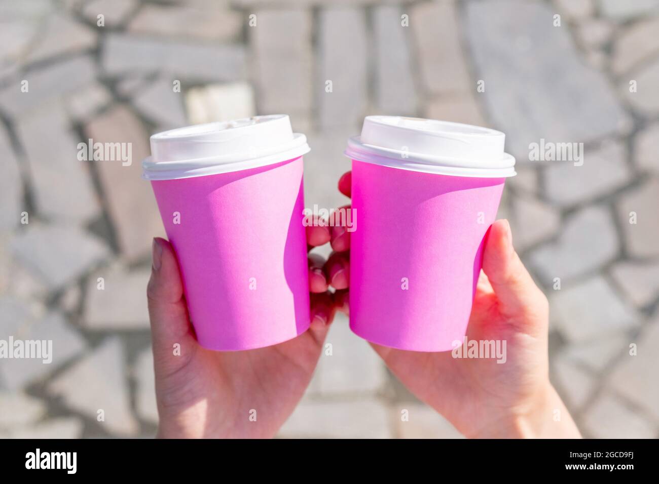 La persona sta tenendo due tazze monouso rosa per caffè o tè Foto Stock
