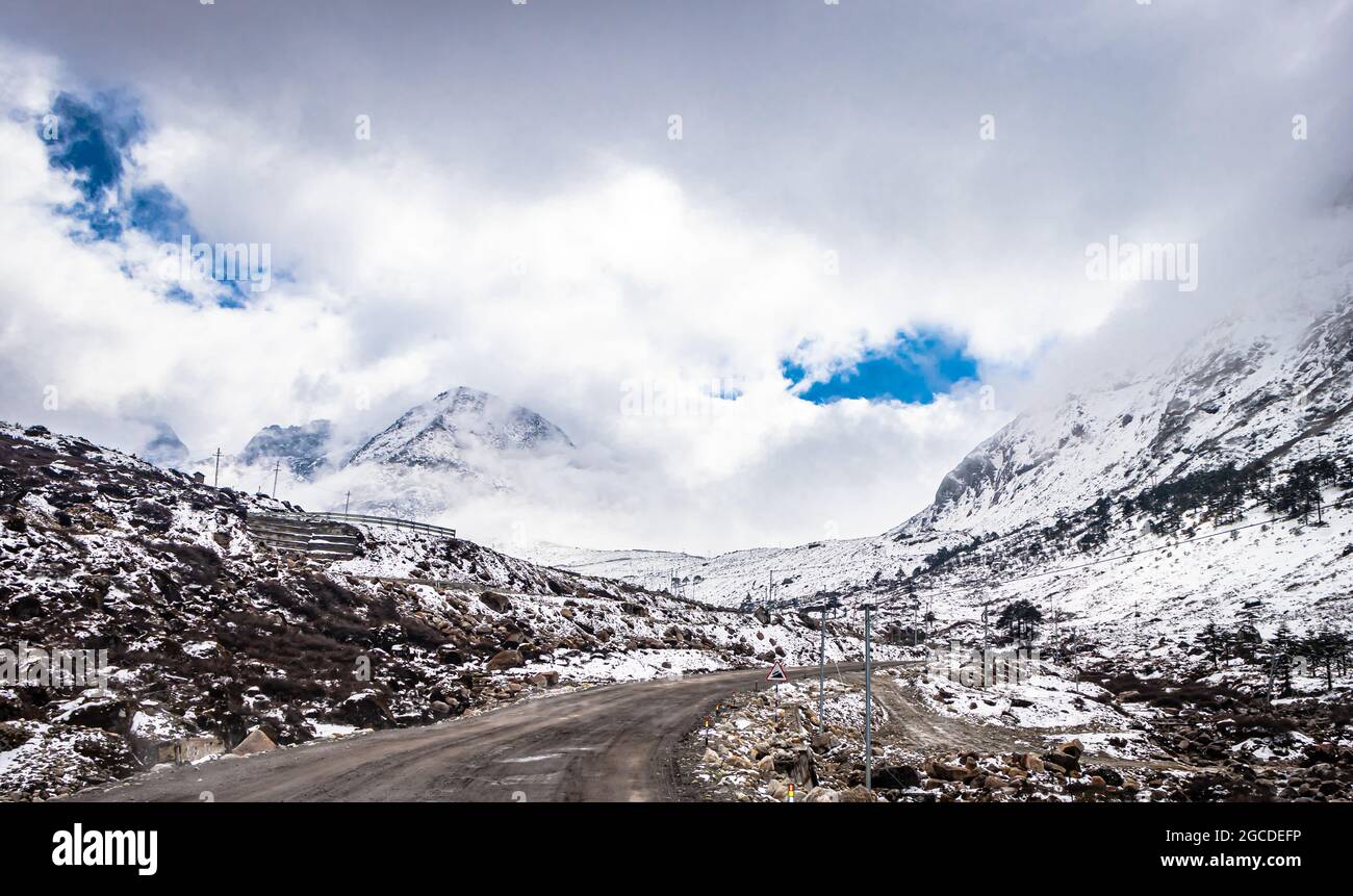strada asfaltata isolata con fondo di montagna con copertura della neve e cielo stupefacente al mattino immagine è presa a sela passo tawang arunachal pradesh. Foto Stock